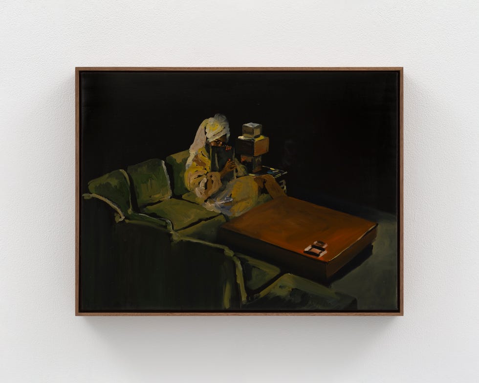 Person reading on a couch in a dark room, painting.